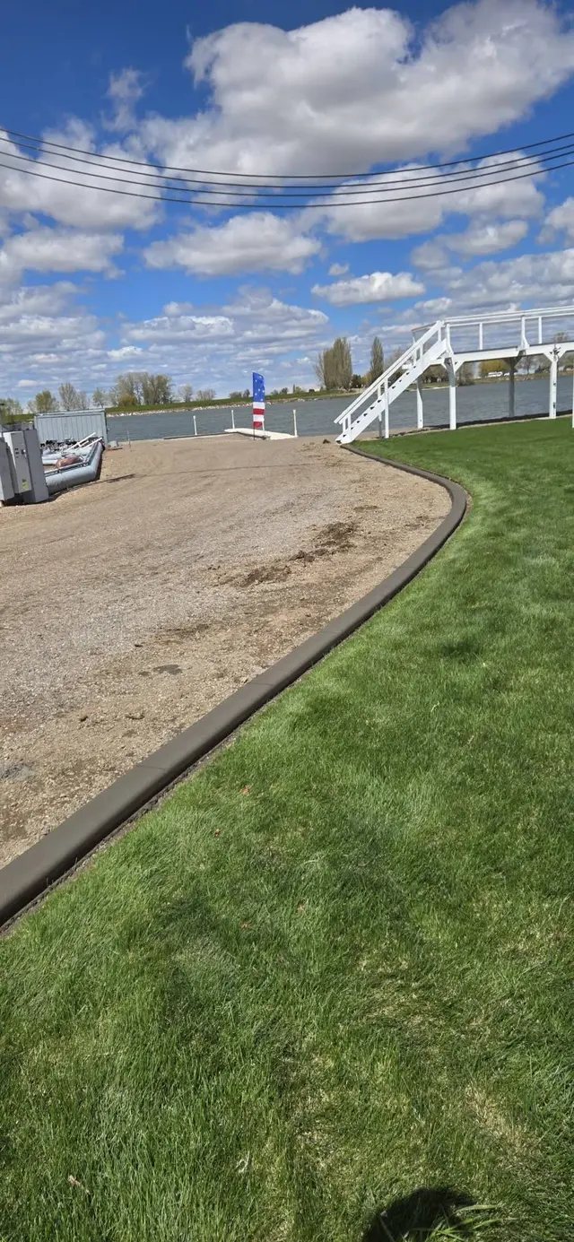 A smooth concrete edge follows the green lawn beside prepared soil.