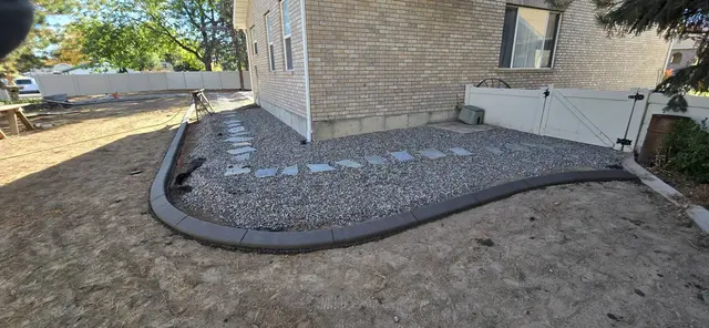 A fresh border wraps a white-gravel bed with stepping stones beside brickwork.