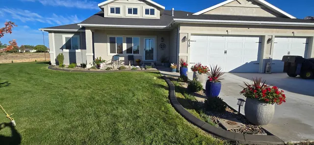 A long dark curve frames lawn, flowering planters and a tidy house frontage.