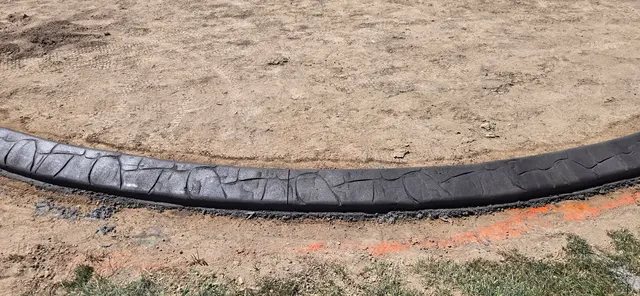 Close horizontal view of dark stamped concrete over a prepared soil bed.
