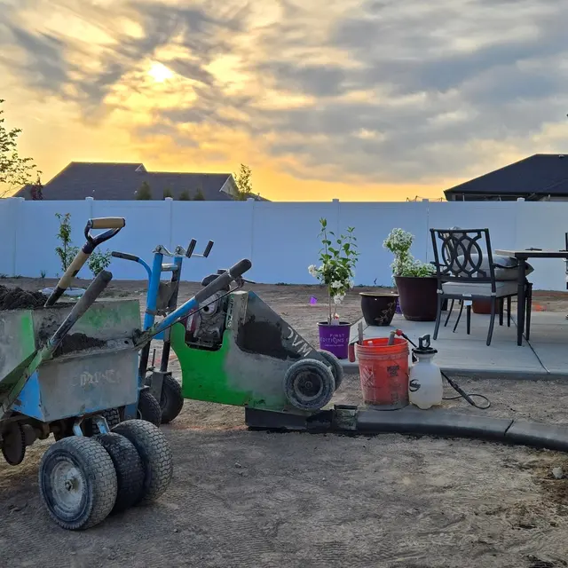 Curbing tools and machinery sit beside a patio under a glowing sunset.