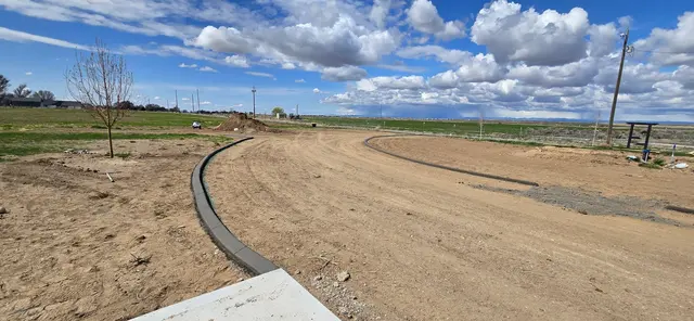A newly installed edge curves from a paved corner into an open prepared site.