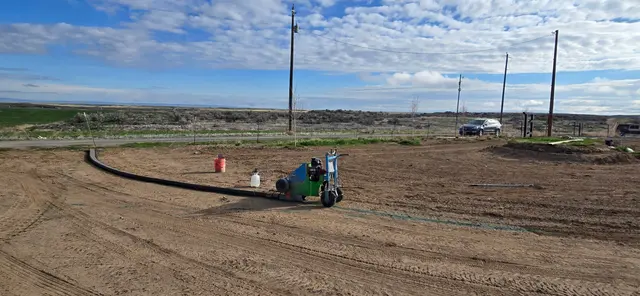 A curbing machine works along a fresh dark curve in prepared soil.