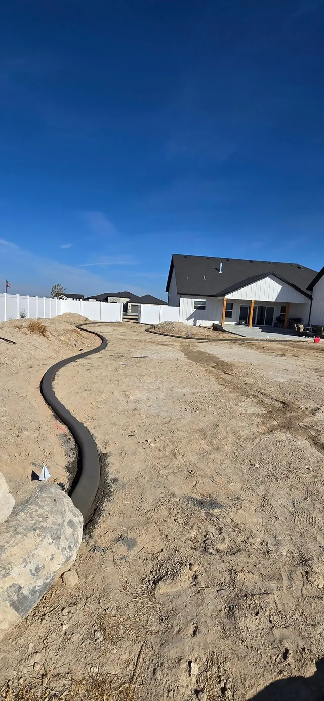 A long dark curve winds through prepared soil toward a new house.