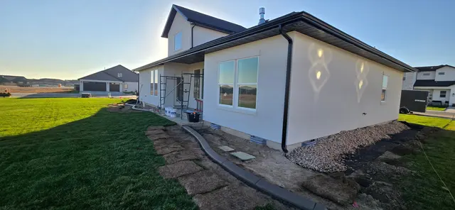 A gray curb borders a gravel and stepping-stone strip beside lawn and a house.