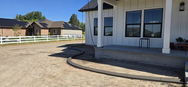 A fresh rounded curb wraps a planting bed at a covered porch.