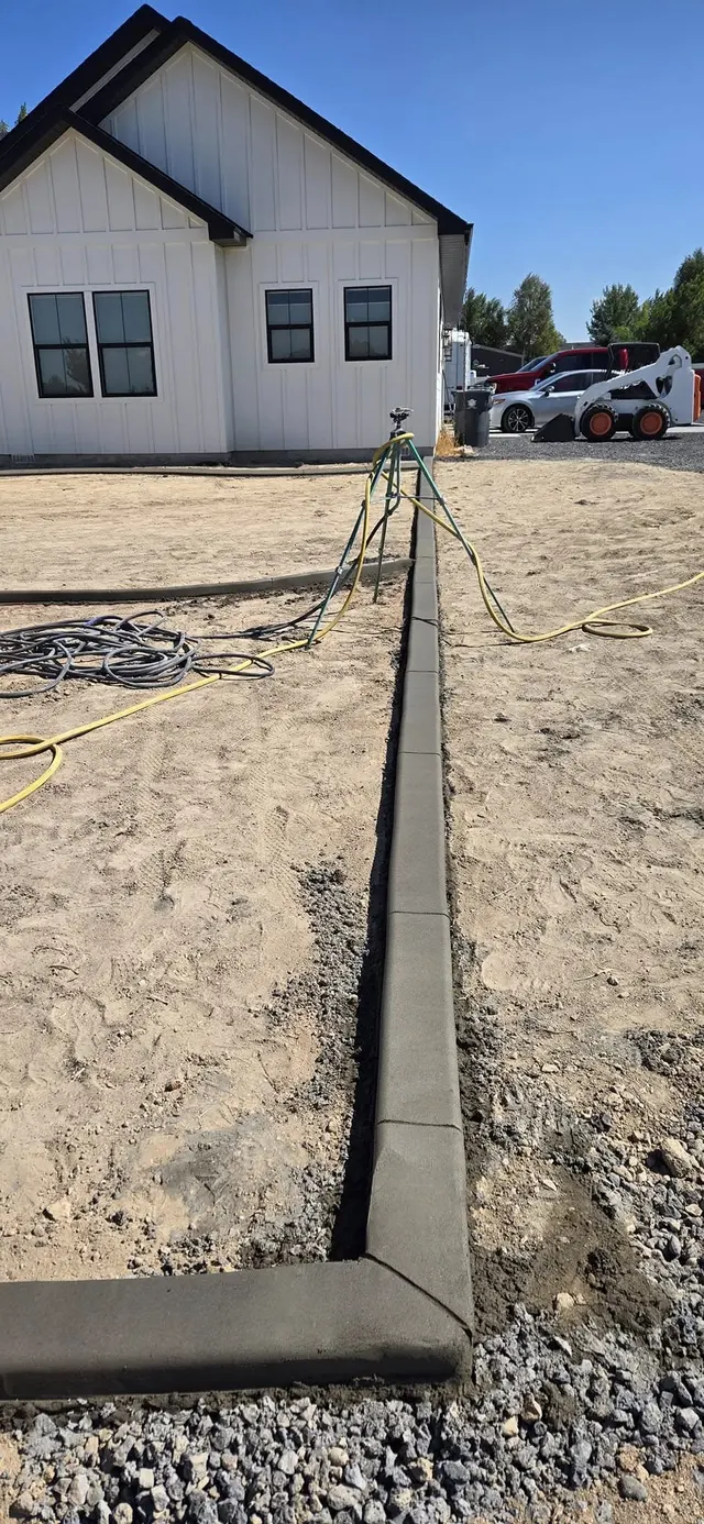 A long straight curb meets a square corner beside prepared ground.