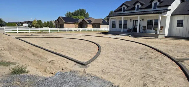 A large house fronts a network of fresh curved and straight borders.