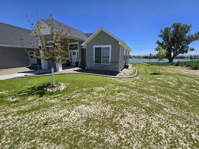 A pale curb defines a young lawn and rock beds around a house.