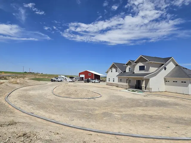 Two broad concrete islands occupy a prepared front yard beside a house.