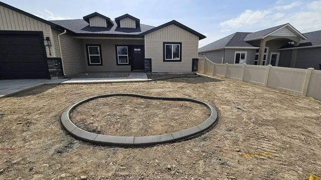 A fresh round concrete ring lies in a prepared yard beside a house.
