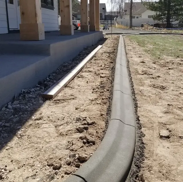A close concrete profile and control joint run beside an unfinished porch-side bed.