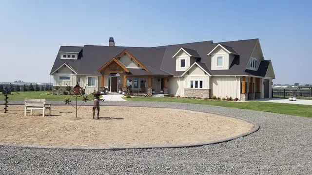 Wide country-home view with a large curbed bare-soil circle inside a gravel drive.