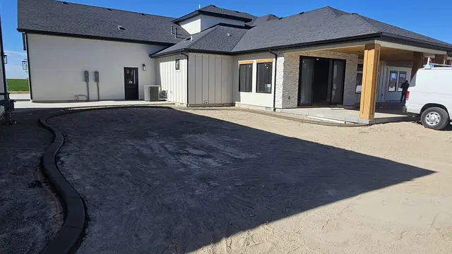 A fresh curved concrete edge defines a planting area beside a rear patio.