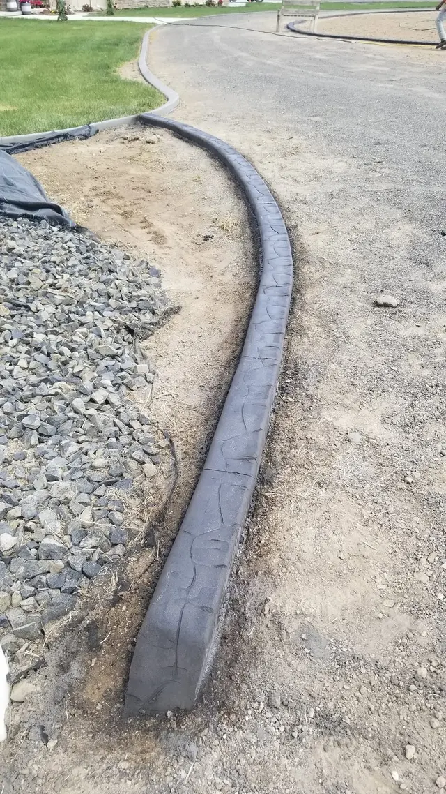 A portrait follows a gray curb between pale stone and a paved drive.