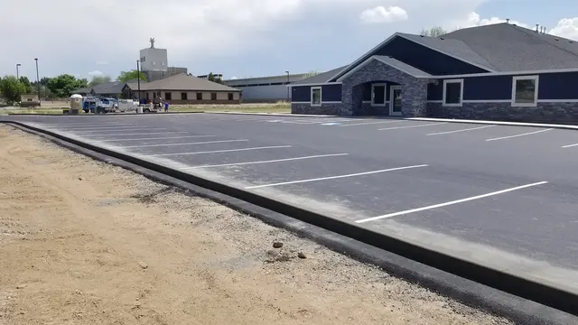 A dark curb follows marked parking bays across a wide paved area.