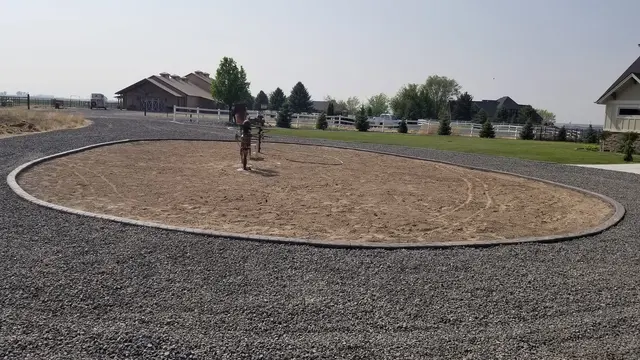 A complete pale concrete ring encloses a large oval bed within gray gravel.