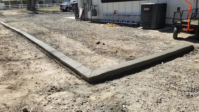 A fresh gray edge forms a crisp right angle beside bare soil and equipment.
